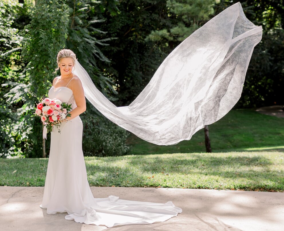 a woman in a white dress holding a bouquet and a long white veil