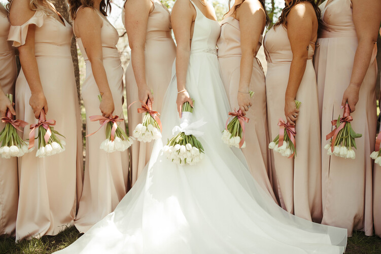 a group of women in white dresses holding flowers