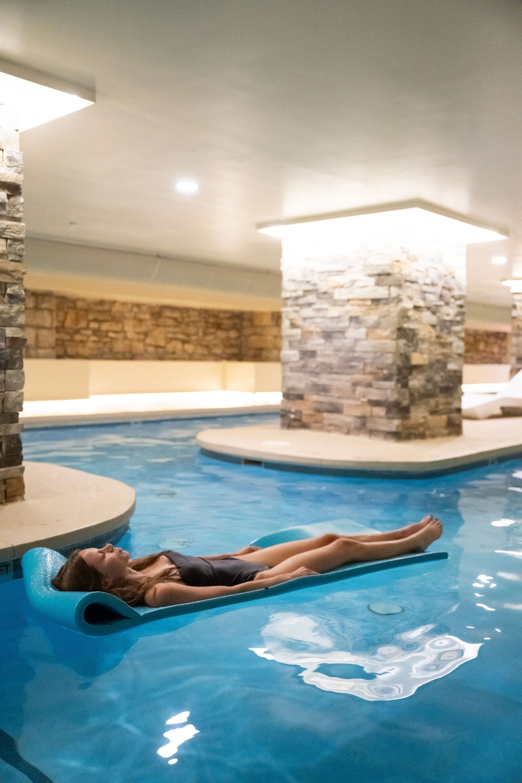 a woman lying on a floating raft in a pool